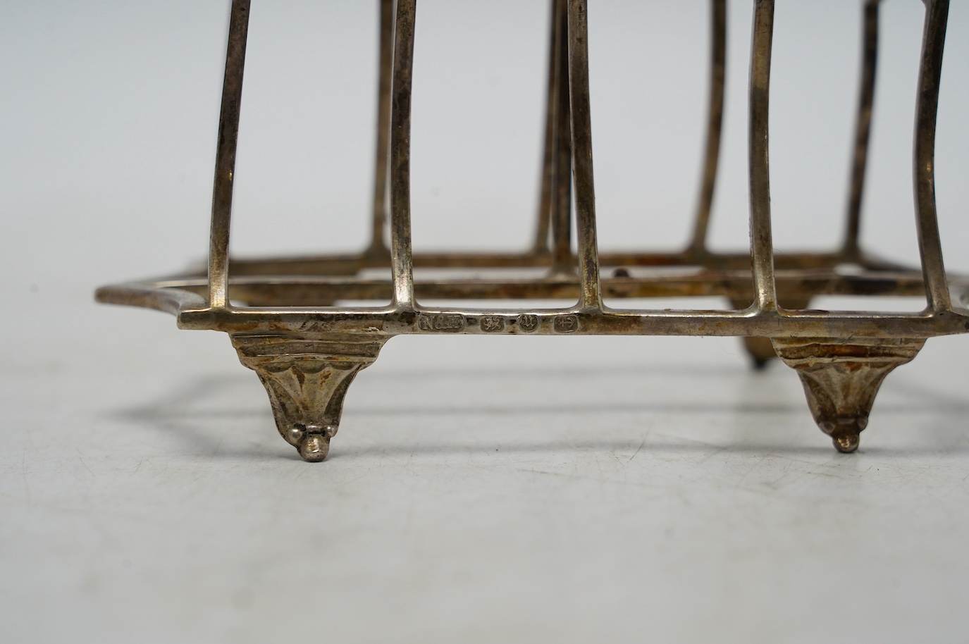 A George VI silver shell dish, Sheffield, 1946, 14.2cm, a modern silver mounted wine coaster and a late Victorian silver five bar toast rack. Condition - fair
